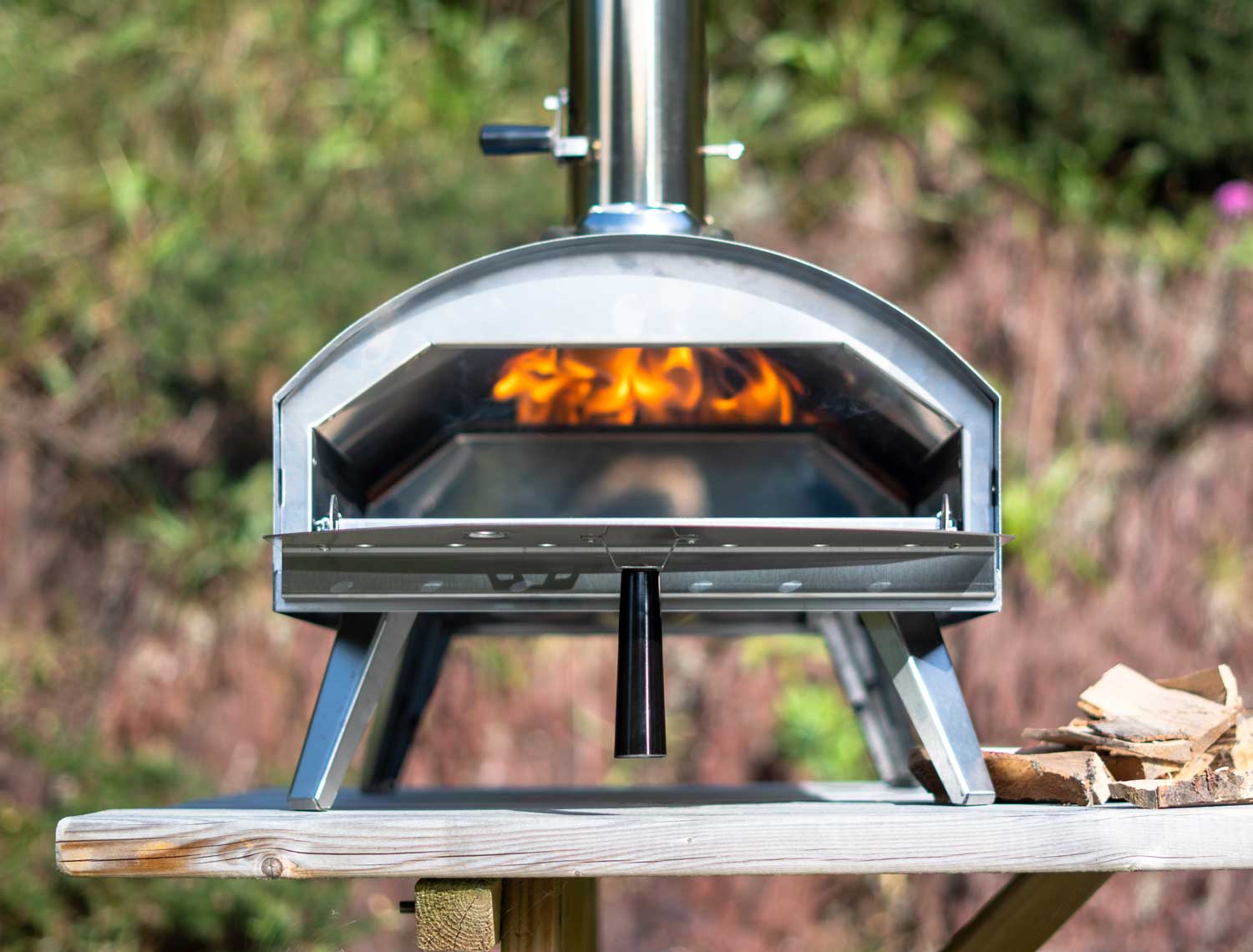 Front view of Venice wood fired pizza oven with the door open.  Fire from wood pellets is visible rising to the top during preheating